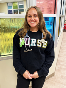 Girl wearing a NURSE sweatshirt and stethoscope.